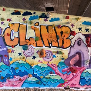 Boulderwand mit bunten Griffen unter einer Brücke