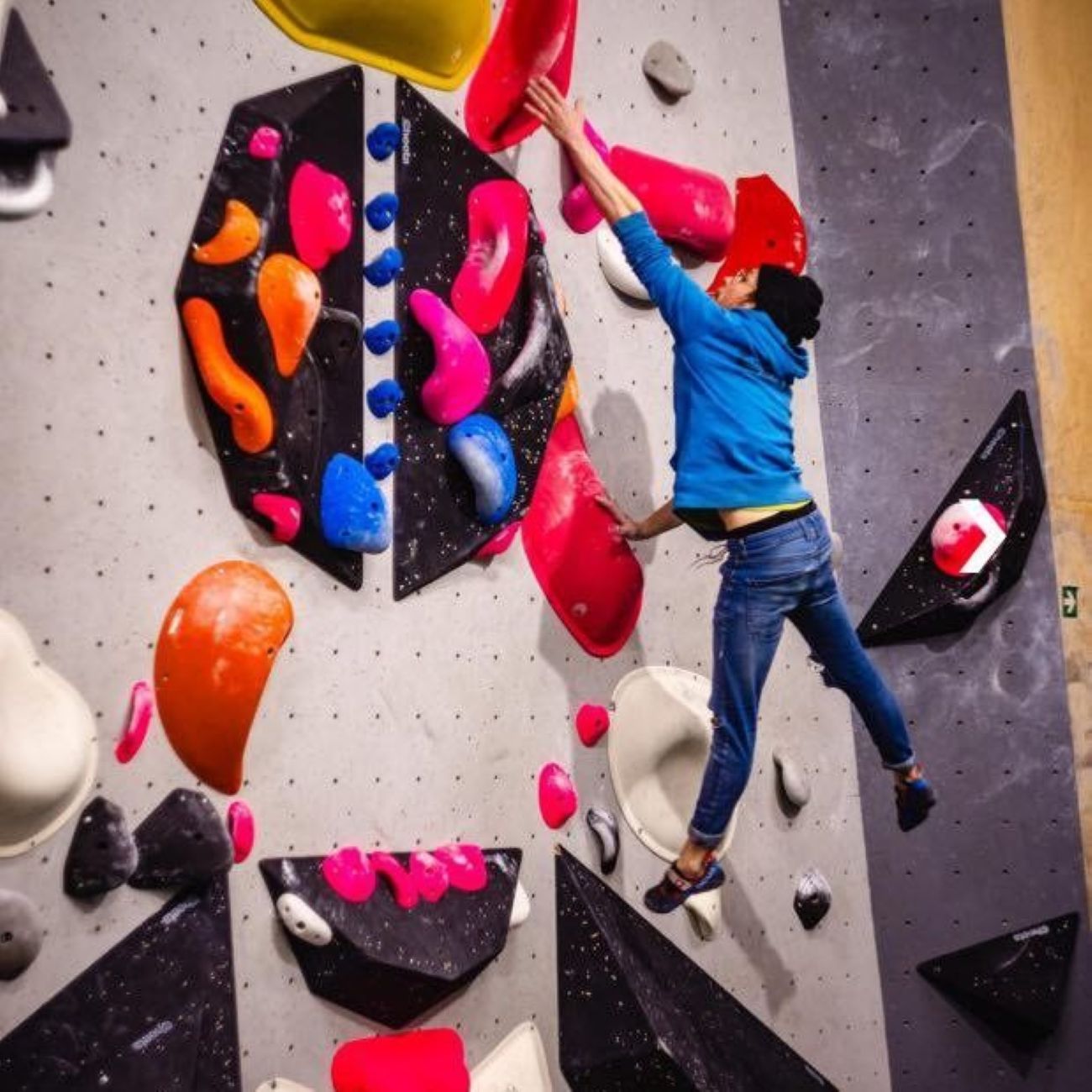 Bouldernde Person im Flug vor Boulderwand