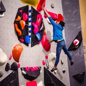 Bouldernde Person im Flug vor Boulderwand