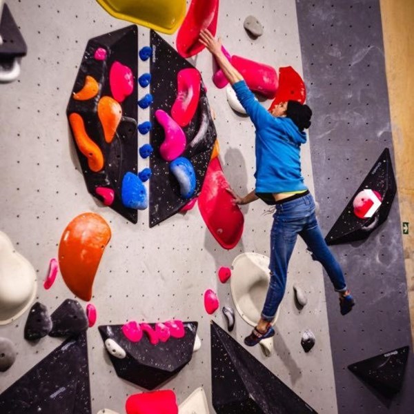 Bouldernde Person im Flug vor Boulderwand